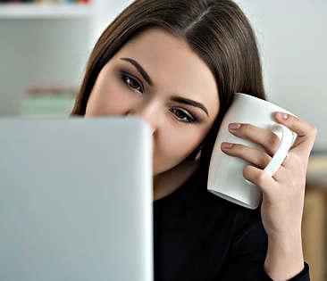 Kündigungsservice - Frau schaut auf Laptop und hält eine Tasse in der Hand 